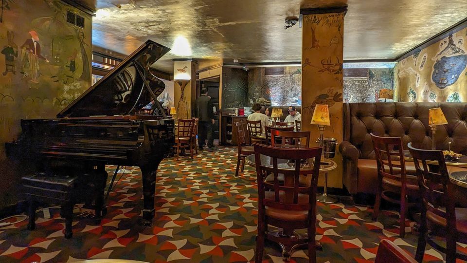 Interior, Bemelmans Bar, Hotel Carlyle, New York City; a sumptuously furnished cocktail bar with gold leaf ceiling, famous murals and a piano