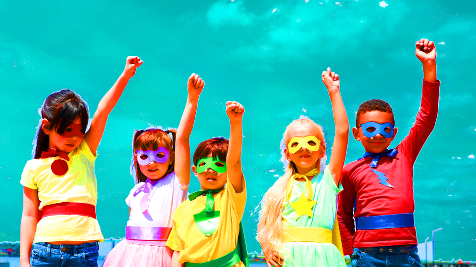 Brightly-colored image of children dressed in simple homemade superhero costumes wearing domino masks raising POWER fists up into the air
