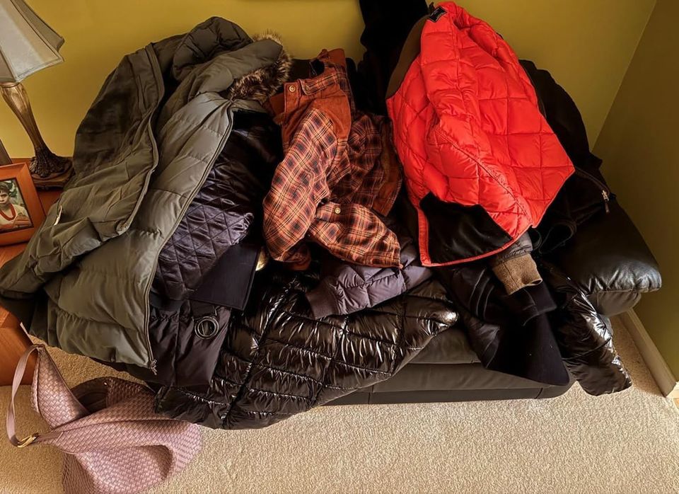 Winter coats piled up on a loveseat.