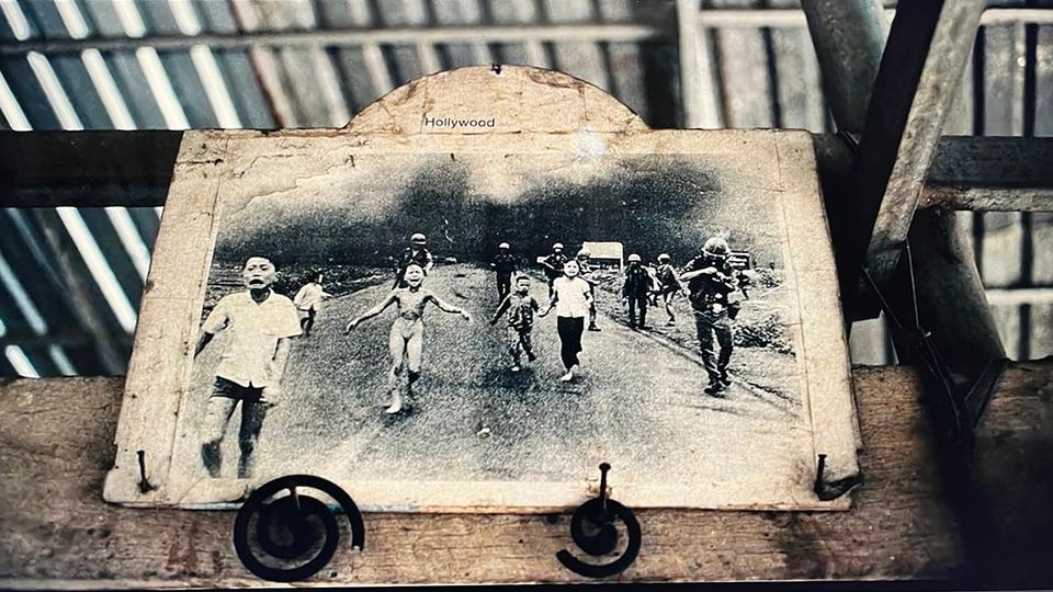 A worn copy of 'The Terror of War' hanging in the tin-roofed bar in Trảng Bàng, South Vietnam, with the small caption "Hollywood" at the t