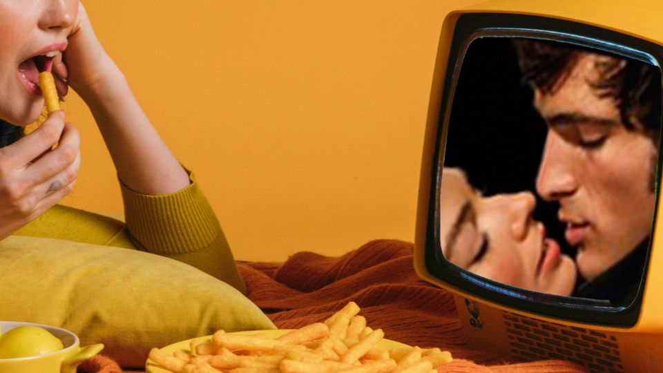 A lady watching a little TV and having snacks with a still from Margot Robbie and Jacob Elordi in 'Wuthering Heights' and about to kiss in the TV