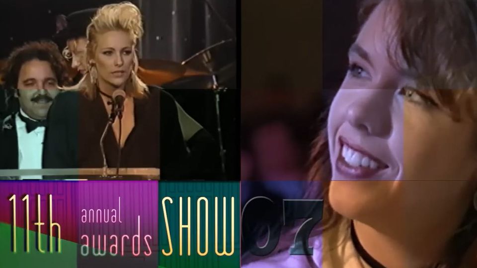 Screenshot from 1994 AVN Awards ceremony shows performer at microphone in red dress and high 90s updo; inset shows another performer in audience, wearing bright lipstick, looking on