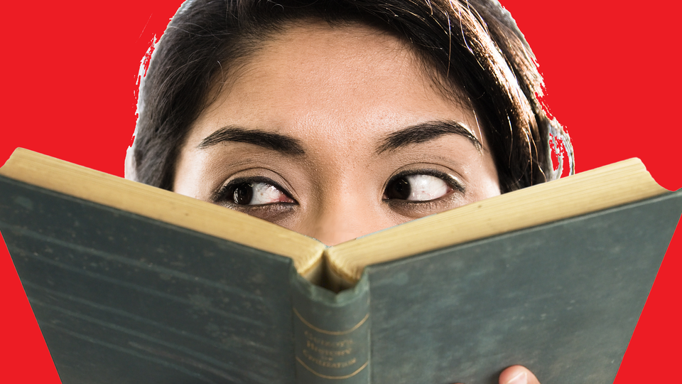 Woman anxiously peering over the top of a book eyes directed to the side