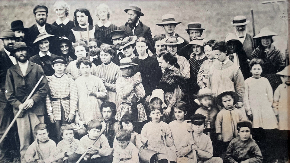 Black and white group photo of about 40 community members, children, elderly, men, and women