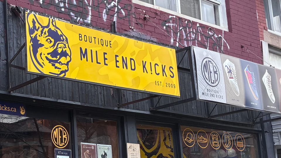 The real shop, Mile End Kicks, in Montréal: bright yellow signage and graffiti on brick shopfront wall