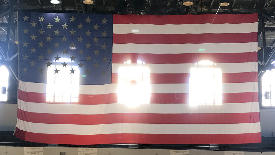 A huge American flag inside the Armory in Baltimore and light is streaming through it