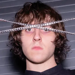 The album art for Cameron Winter's Heavy Metal. It features a young white man (Cameron Winter) with floppy brown hair and two chains in an x across his face.