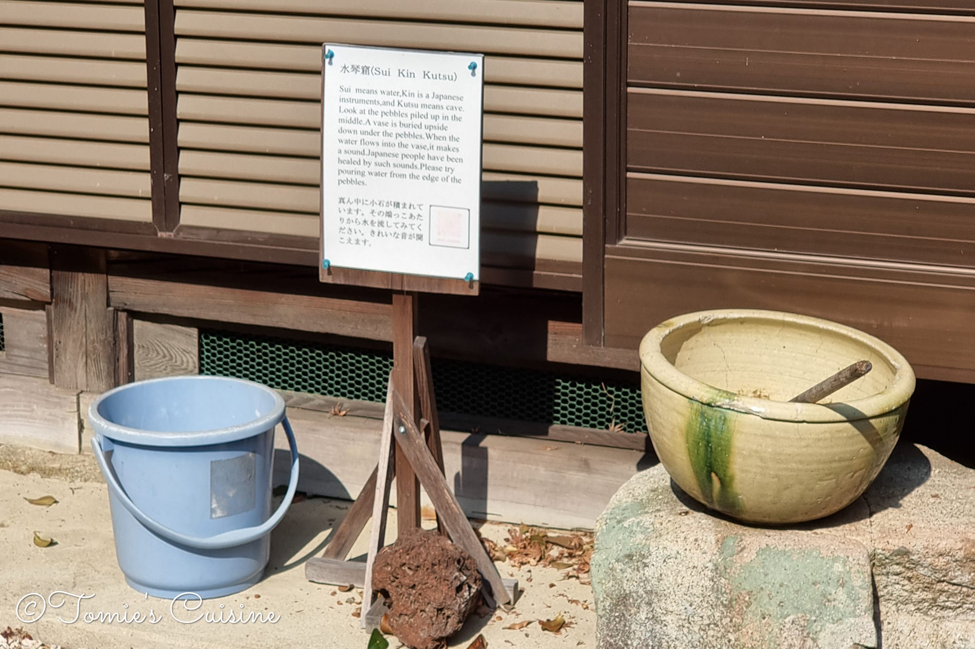 Suikinkutsu (水琴窟) water basin and explanation board in a cafe garden between Nakatsugawa and Ochiai