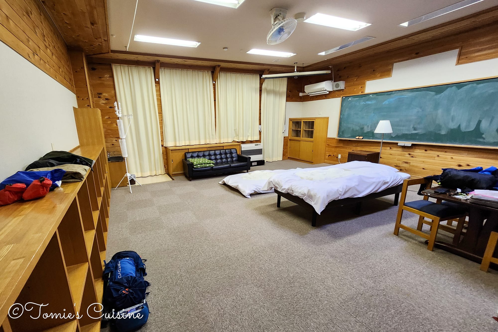 Our classroom bedroom at Magome Furusato Gakko, with a bed, a futon and a blackboard