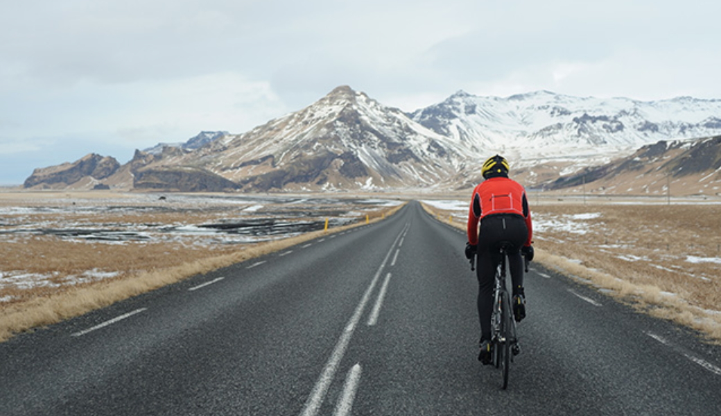 man in red jacket riding bike on bridge