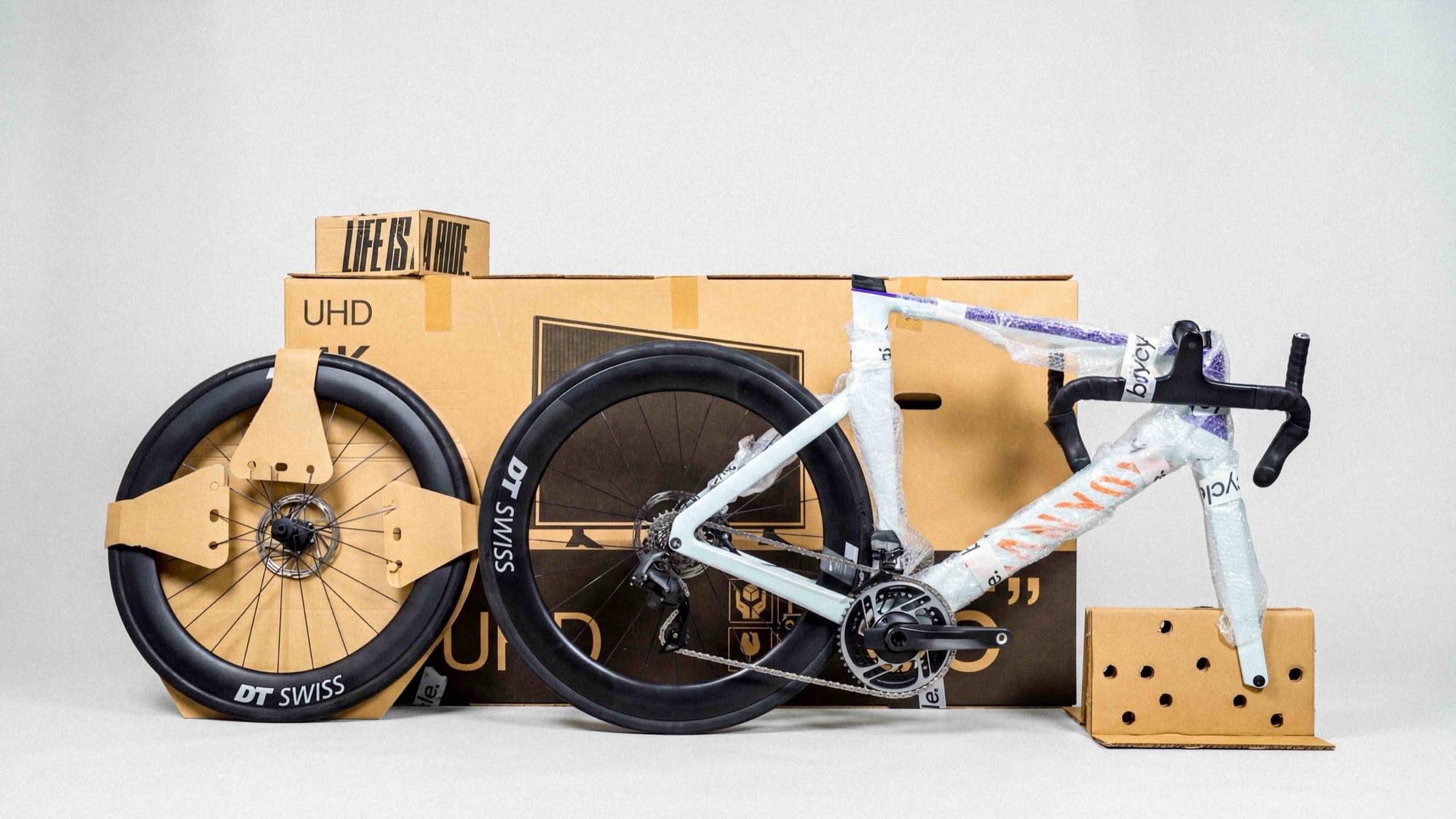 A disassembled Canyon road bike with DT Swiss wheels packed beside a buycycle shipping box