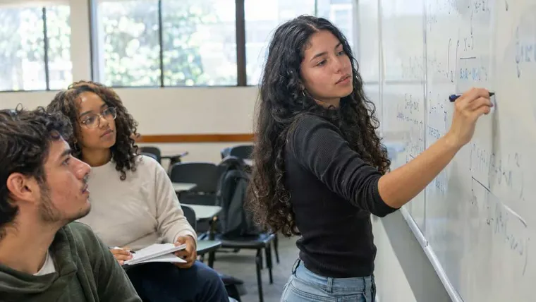 Ilustração gerada por IA: estudante resolvendo cálculos em um quadro com colegas.
