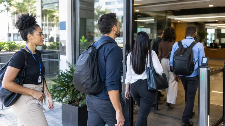 Ilustração gerada por IA: trabalhadores entrando em uma empresa pela manhã.