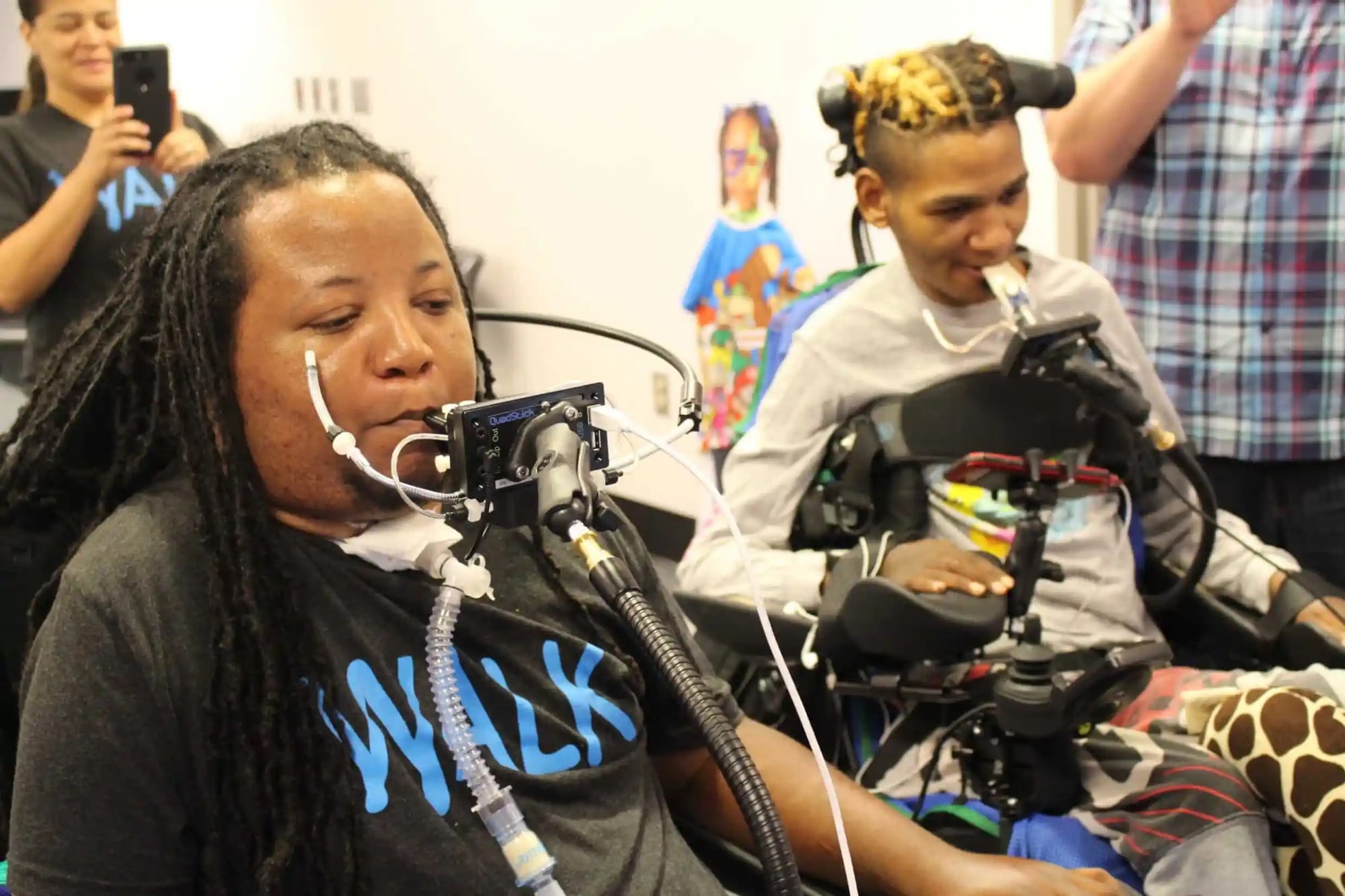 Two Black men use QuadSticks to play video games.