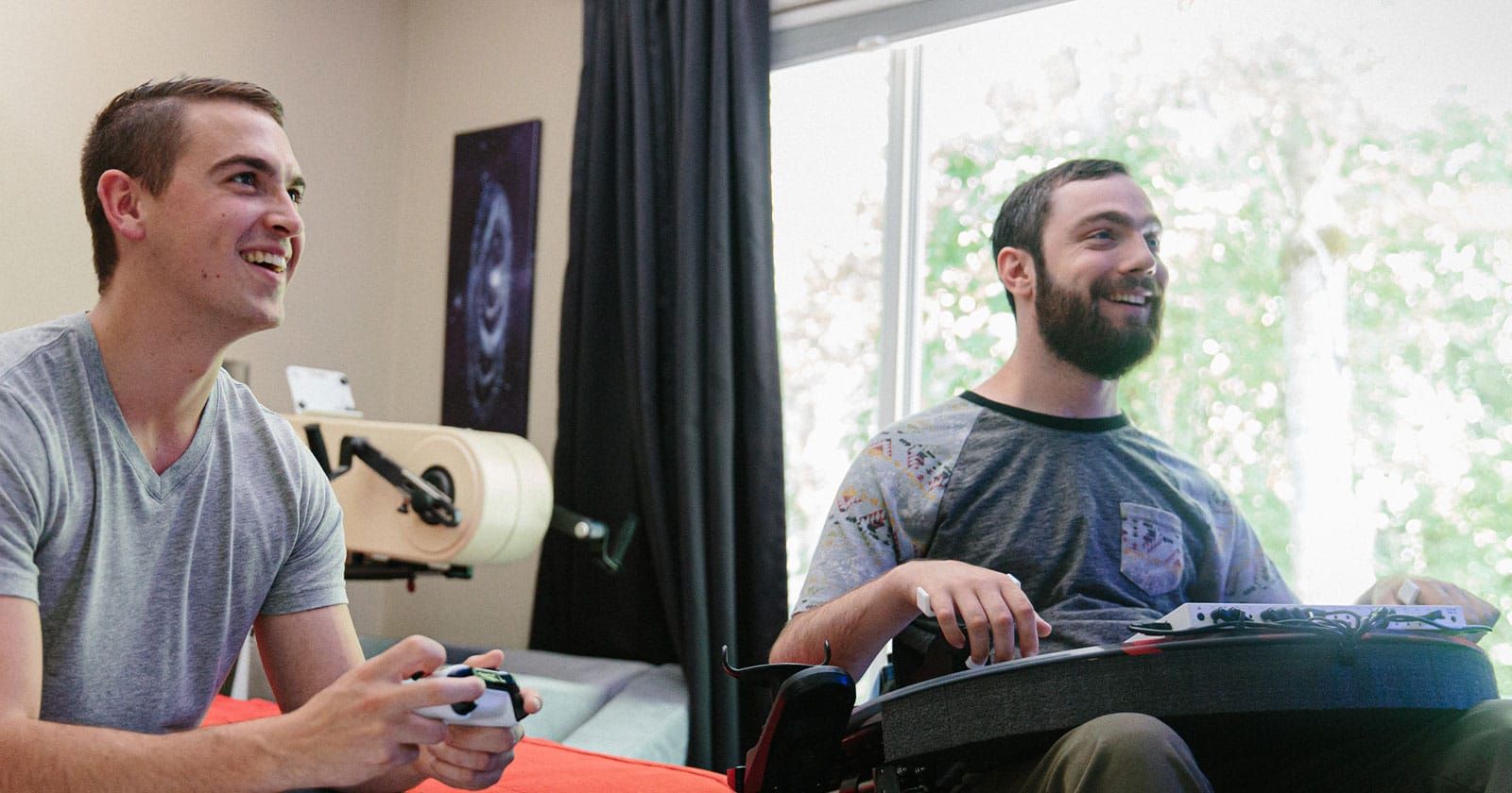 A man plays a game with his friend using the Xbox Adaptive Controller.