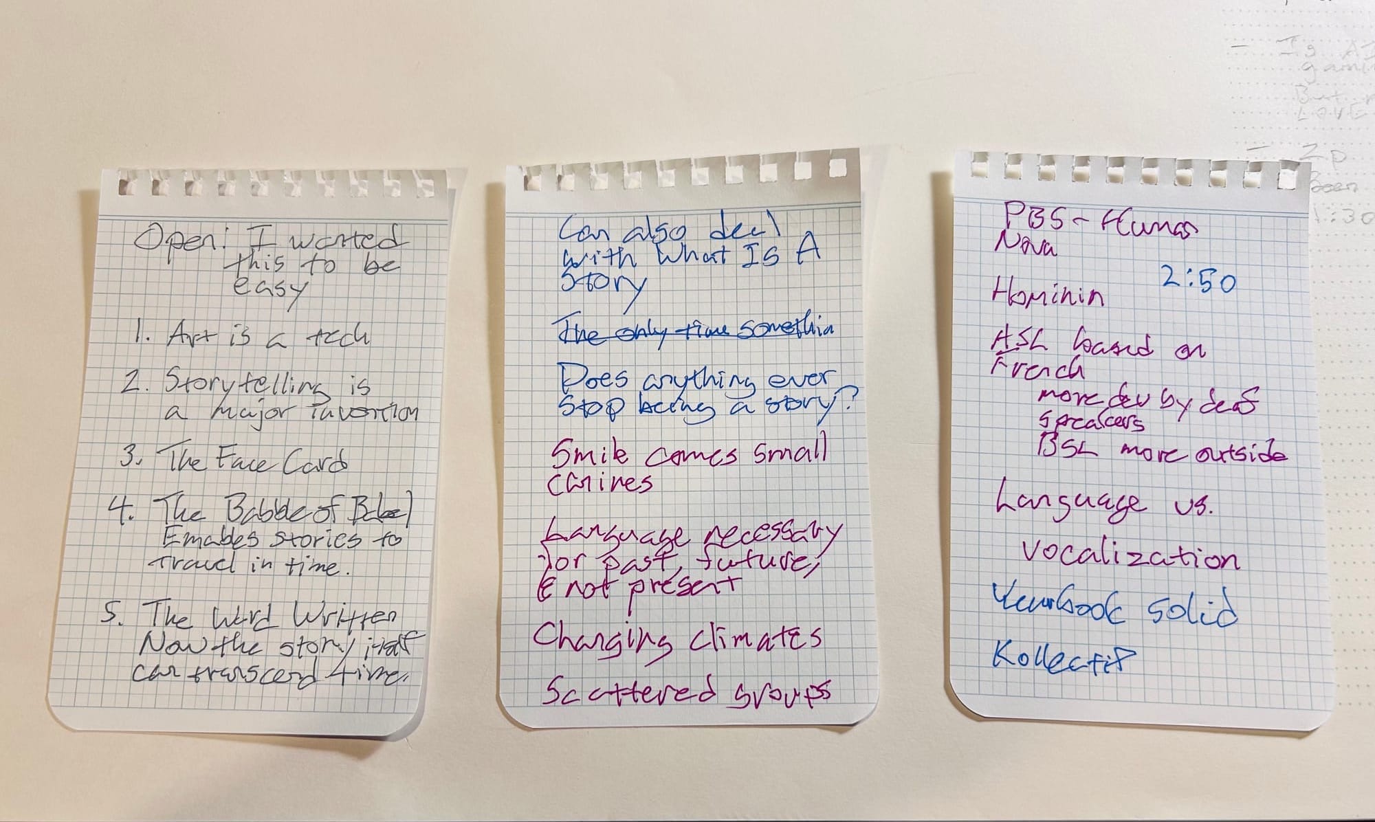 Photo of three sheets torn from a notebooks, with notes in various colors.