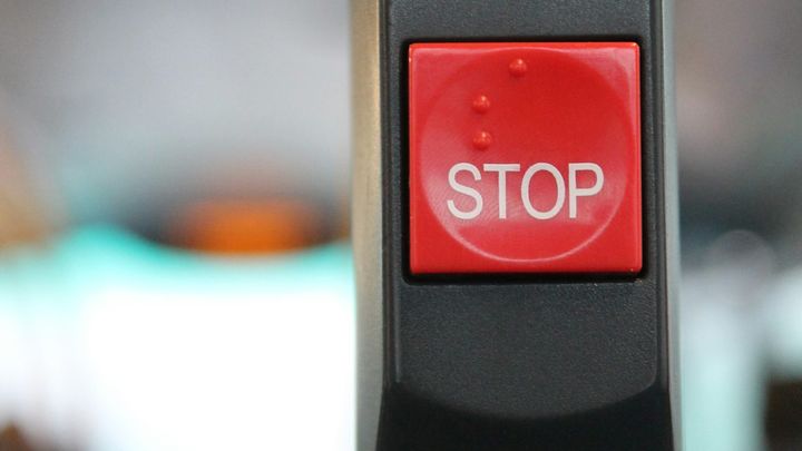 Closeup of a square red button marked “STOP."