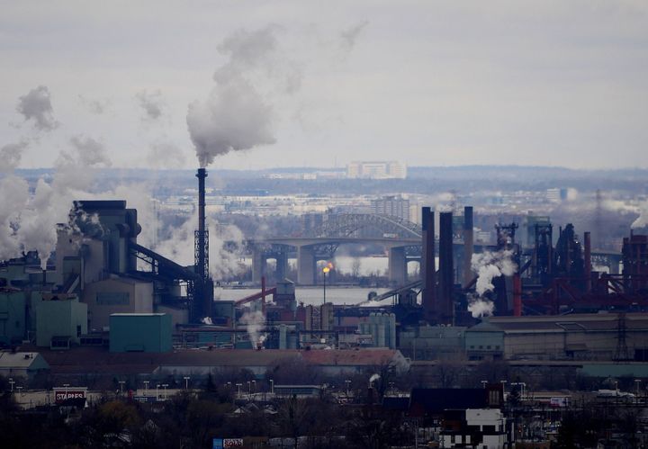 a large steel mill on the shore of lake ontario. the lake and steel bridges are visibile in the background