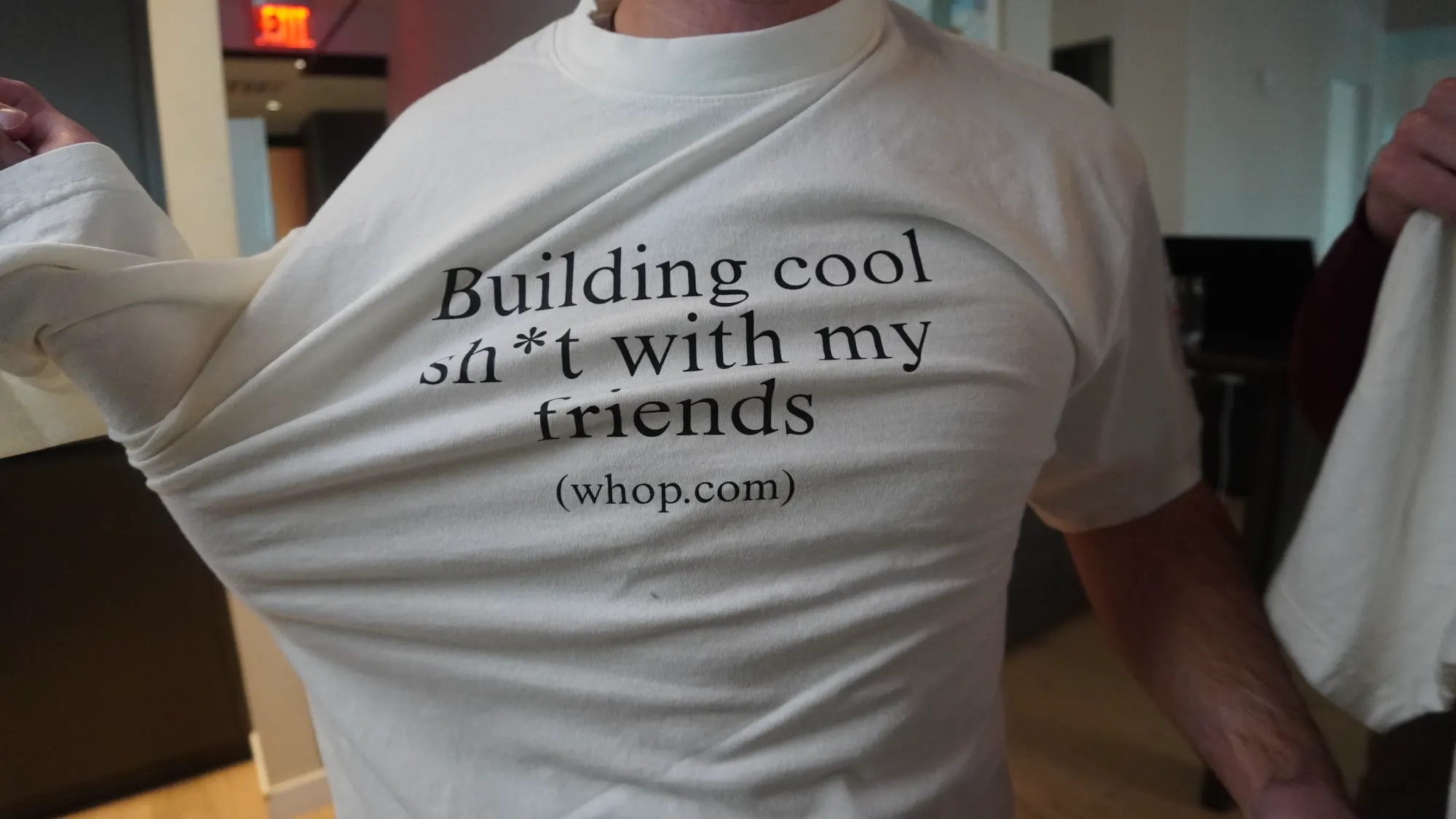 Putting on a tshirt that says 'building cool sh*t with my friends (whop.com)