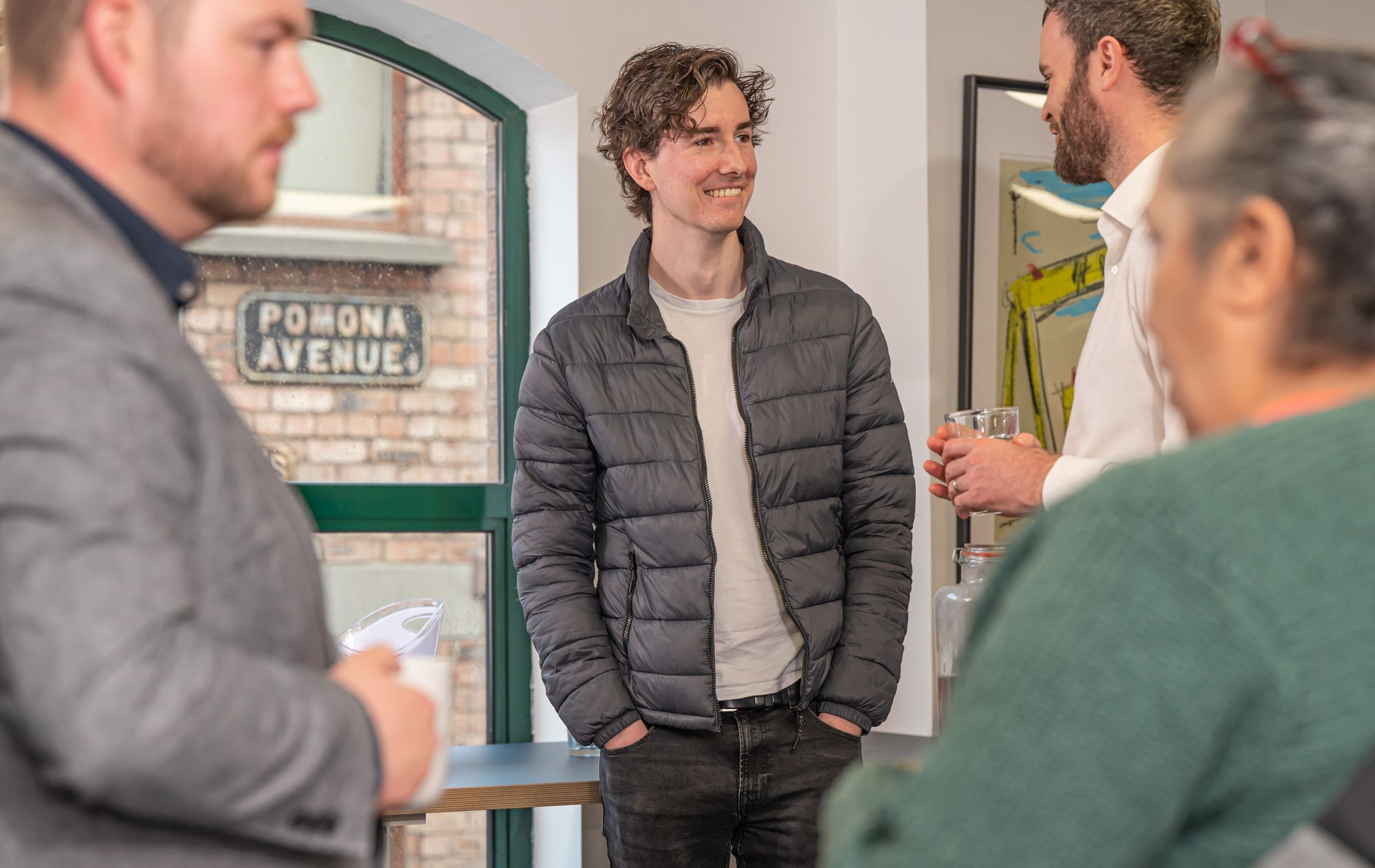 Four men chatting casually in an office space drinking coffee