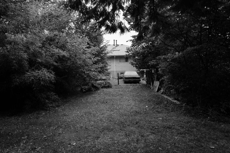 Car behind house, its driveway empties into a public park; West Central Burnaby
