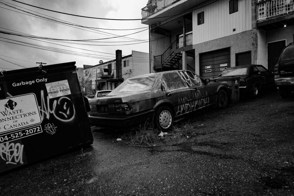 Graffiti covered car parked behind business and residence; Collingwood, Vancouver