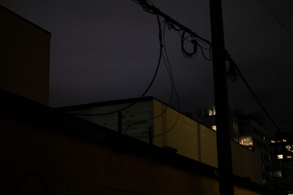A picture of the night sky between rooftops glowing purple-grey; Mount Pleasant, Vancouver