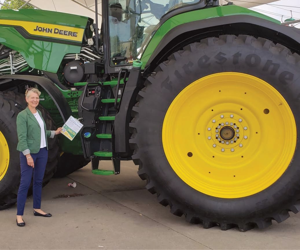 Sare stands in front of a John Deere 8R 540 tractor at the Iowa State Fair, holding the price tag of $904,000.