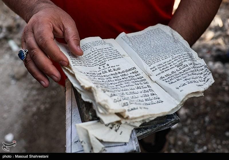 This picture shows a damaged Hebrew religious text being held amid the wreckage of the historic Rafieinia Synagogue in Tehran, which was destroyed by a U.S.-Israeli bomb attack on April 7, 2026.