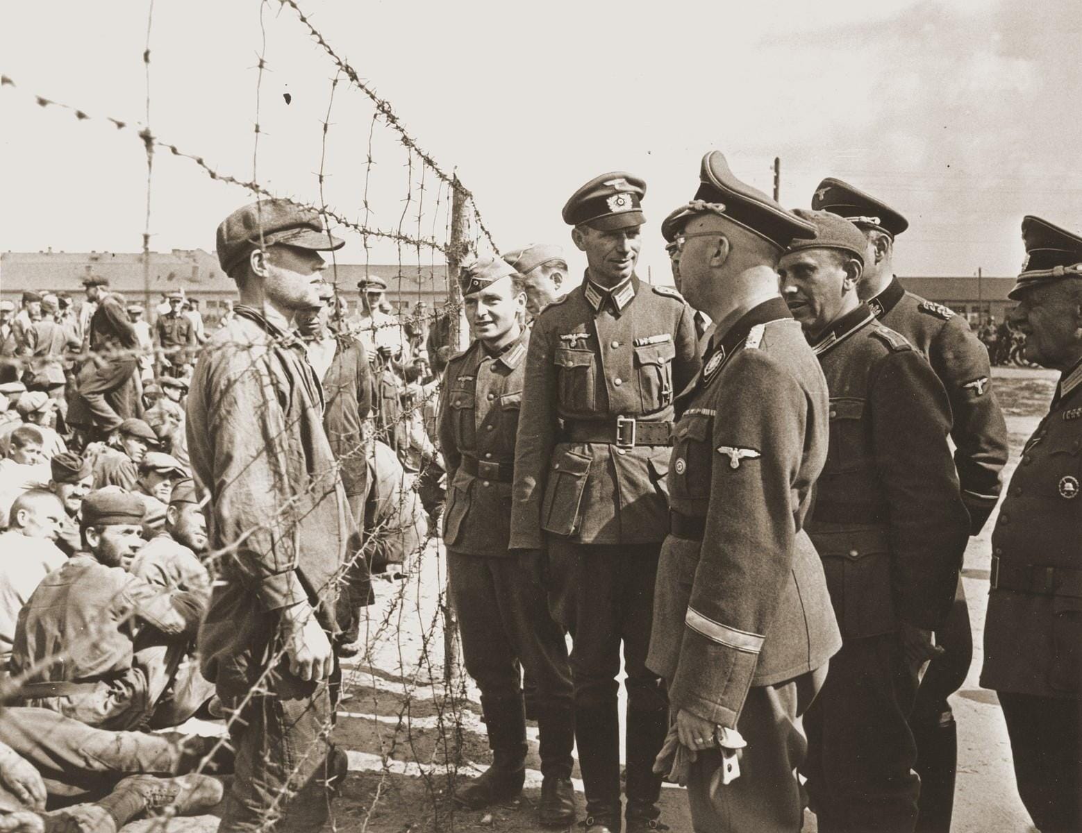 Heinrich Himmler visits a Nazi concentration camp. The end phase of Milton Friedman’s fascist economic policies, were they applied, would lead to similar conditions.