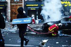 A “black bloc” provocateur stands in the midst of carnage brought about by violent street riots in Paris, October 17, 2026. Are these riots part of a “gang-countergang” operation to…