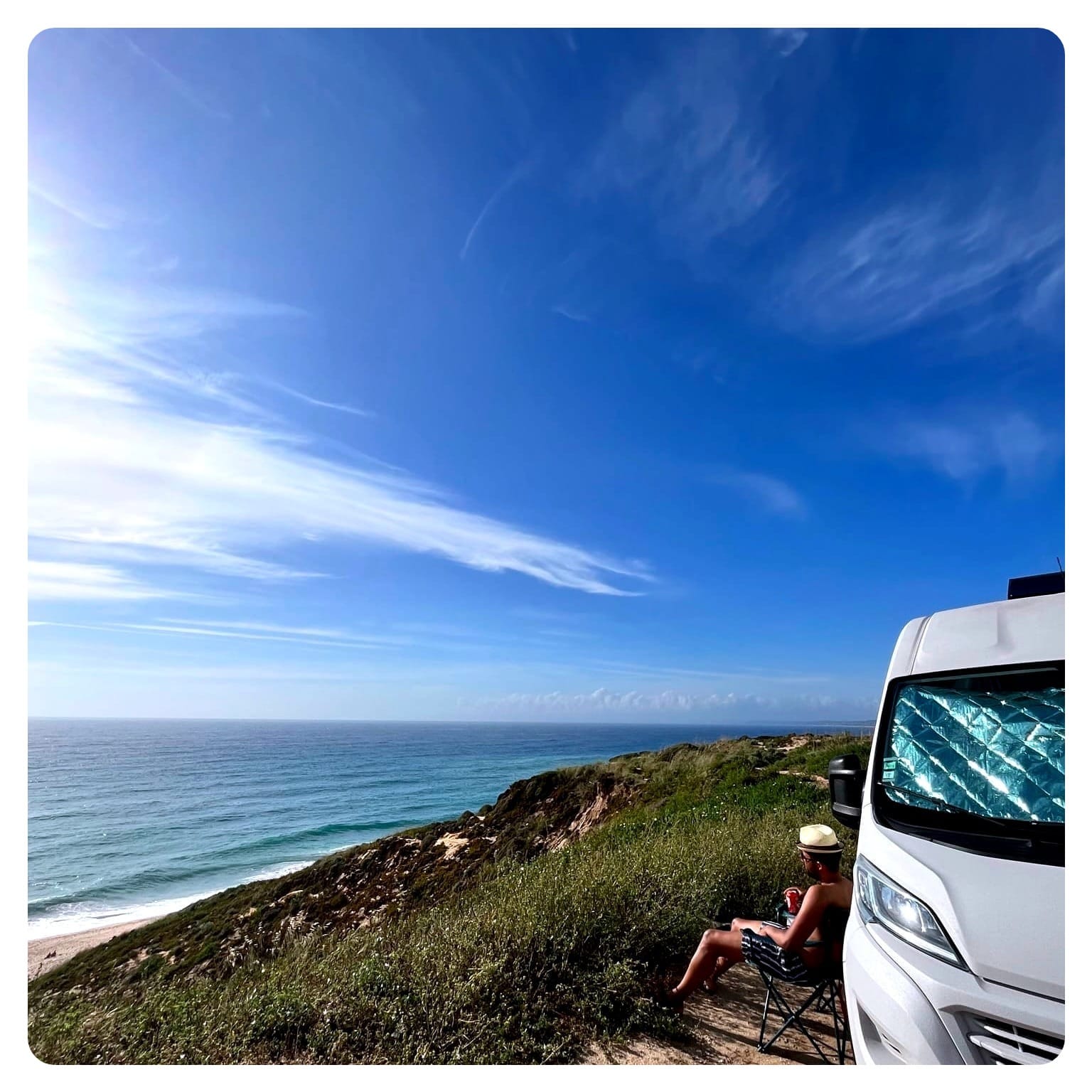 Van Life man beside camper van on cliff side overlooking beach and sea in Portugal