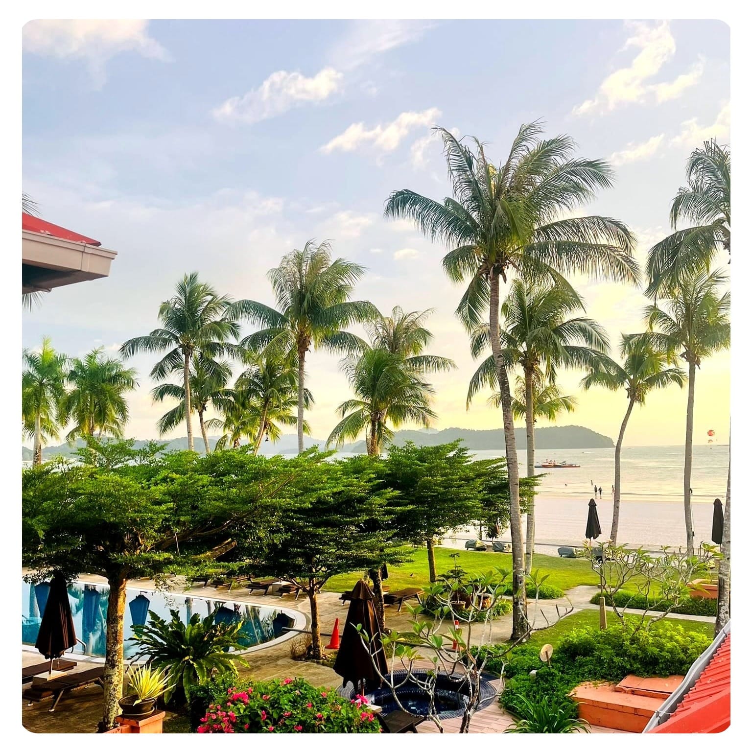 Langkawi beach sunset picture from hotel balcony with palm trees and pool