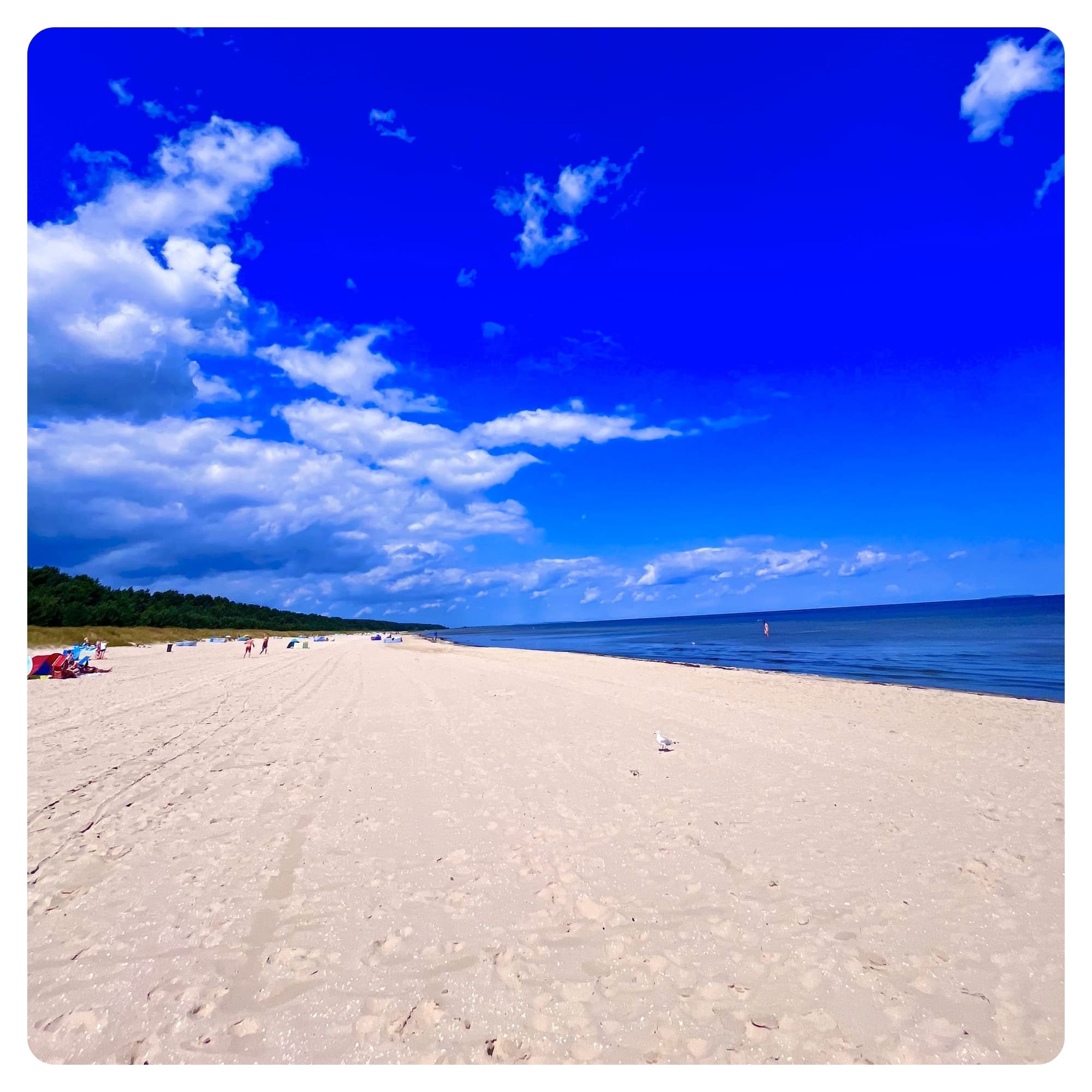 Long and wide sandy beach with blue sky and blue sea
