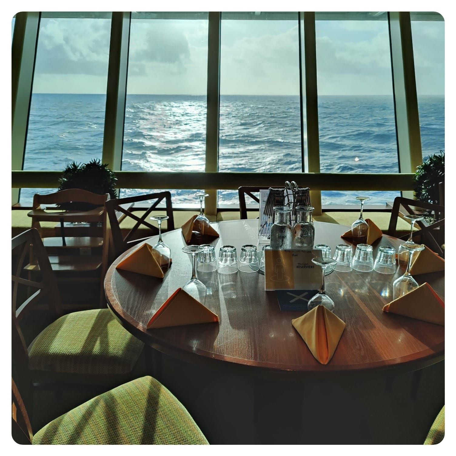 a table with glasses and bottles on it by a window with water