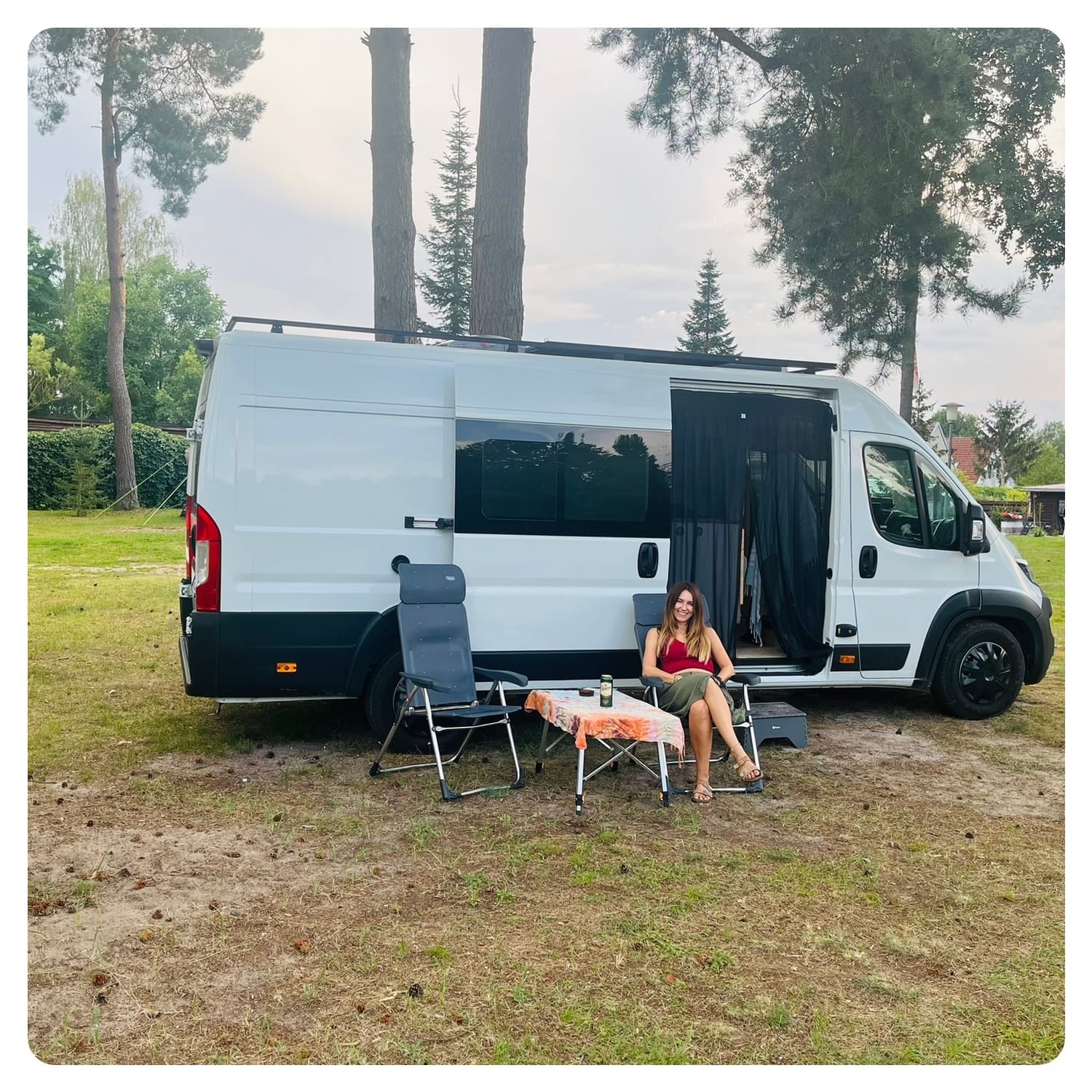 vanlavita woman sat outside camper van on campsite