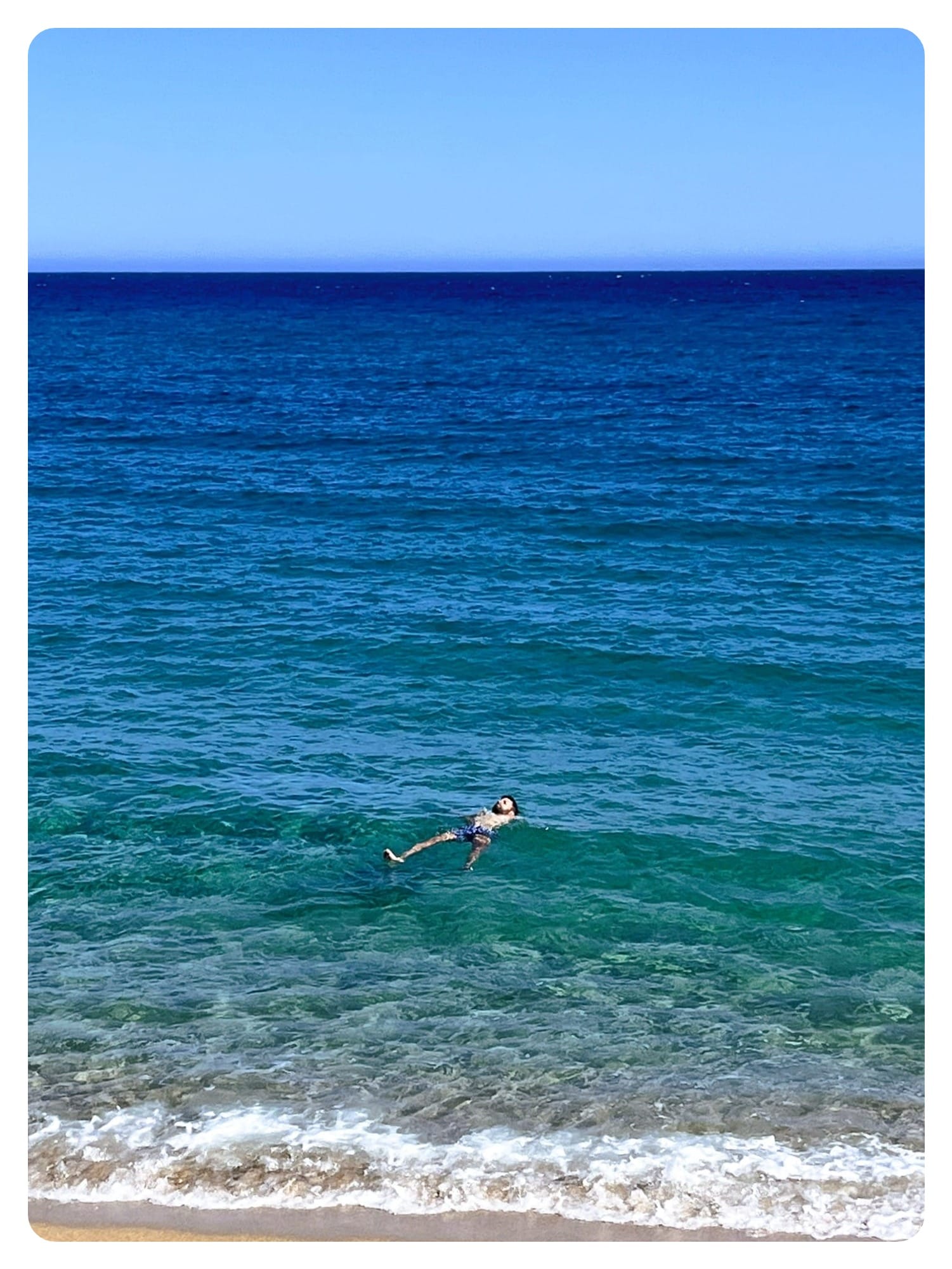 man floating on back in turquoise sea