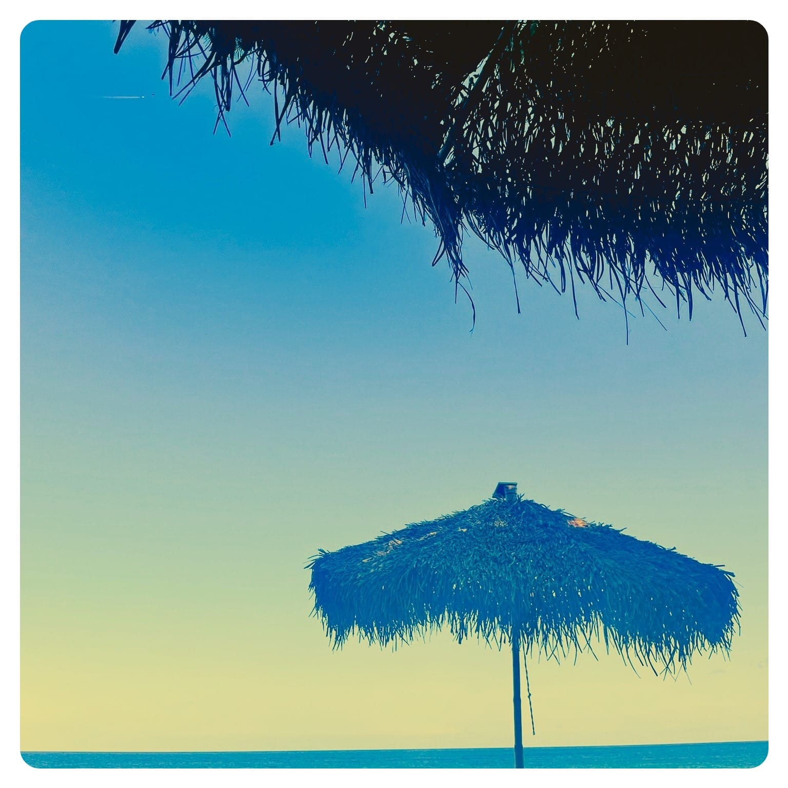 view of grass sun parasol with blue sea in background