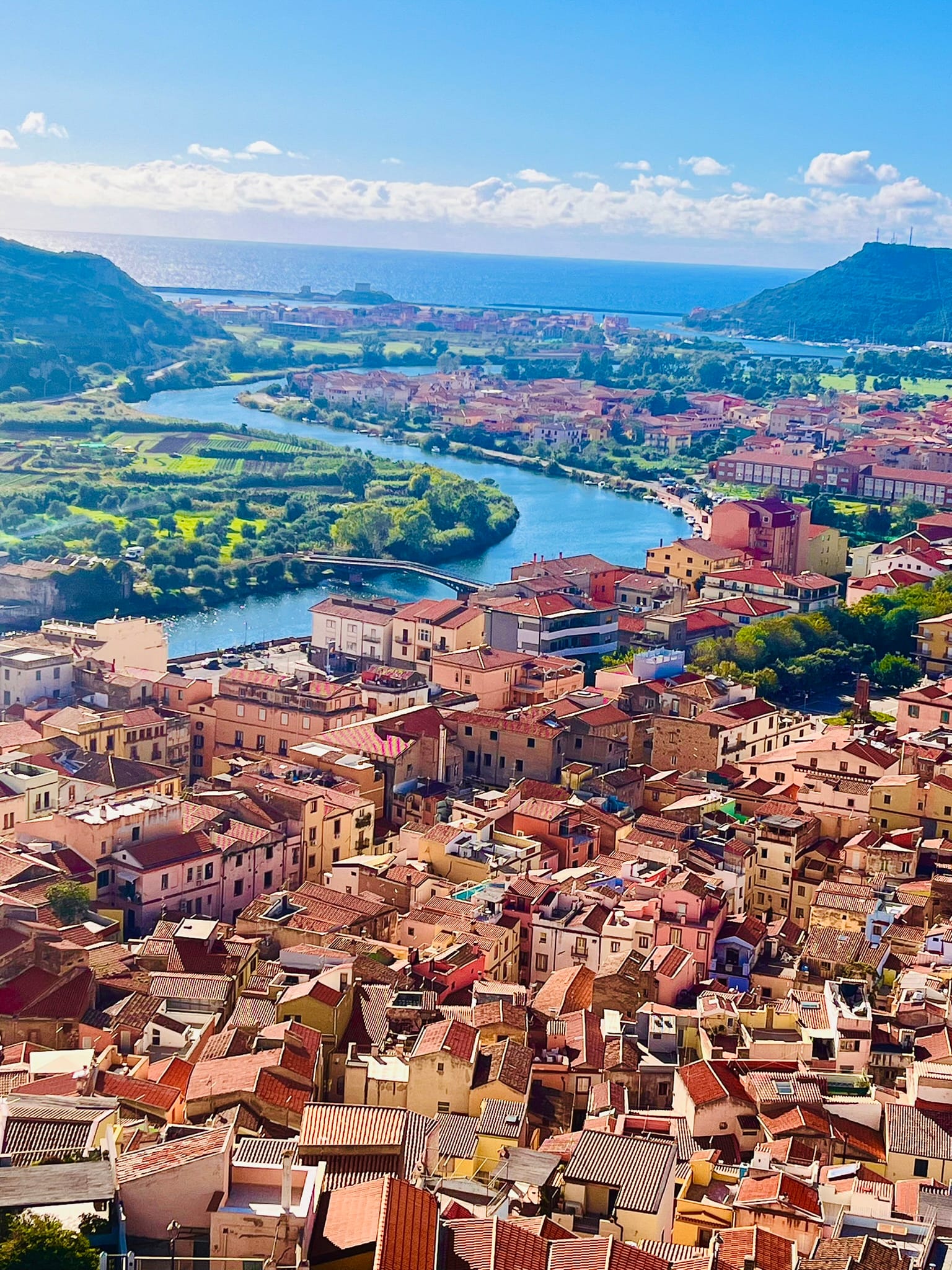 panoramic view over terrocota rooftops and sea in background in Bosa