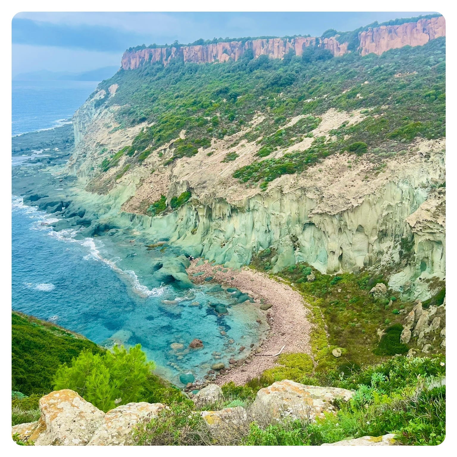 turqouise sea in a bay with green rock formations