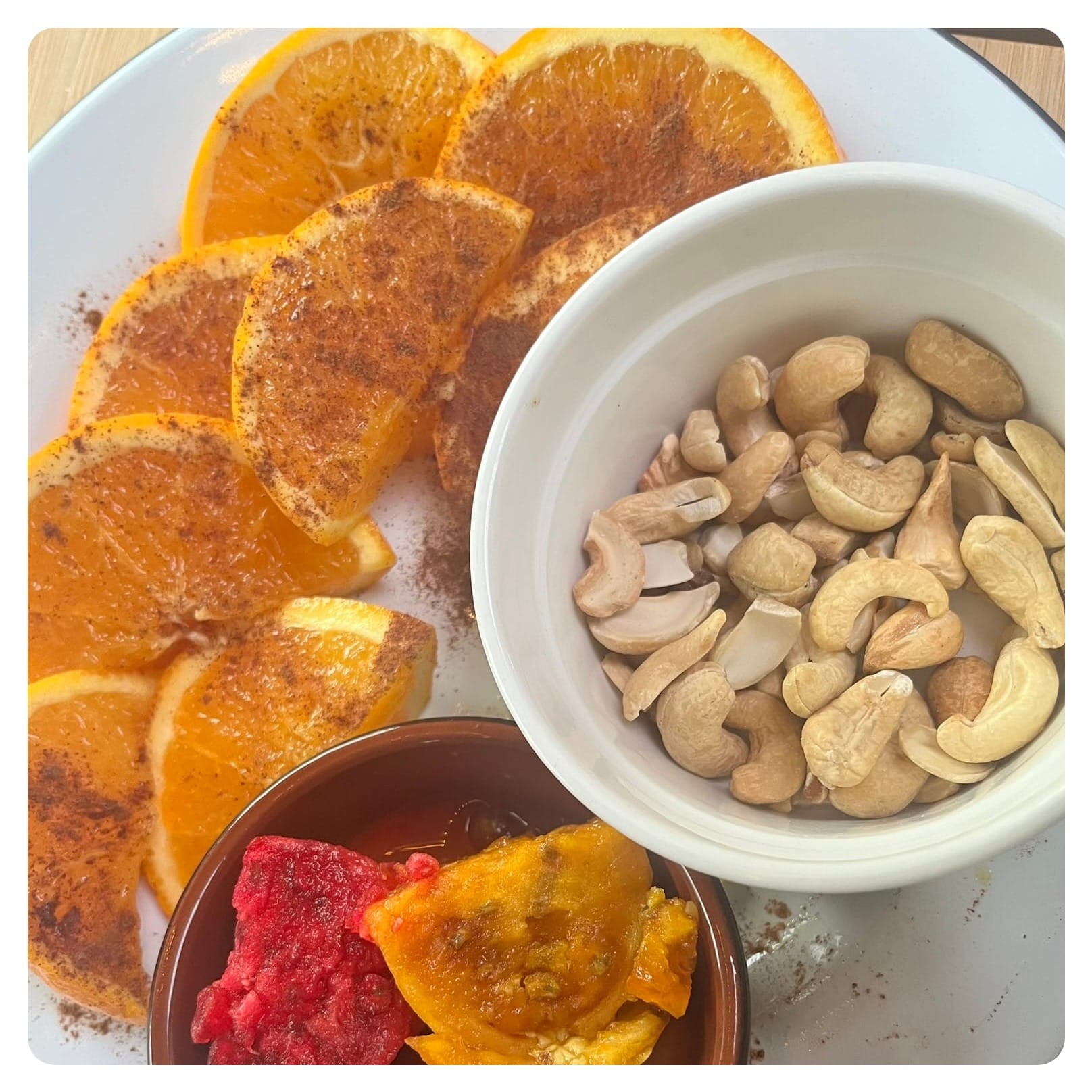 cashew nuts and orange fruits on a white plate