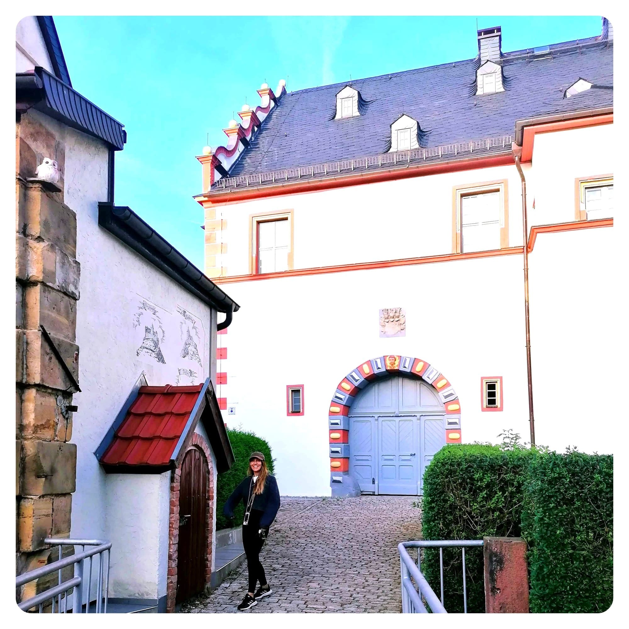 vanlavita woman stood next to a wooden door in the courtyard of a white castle