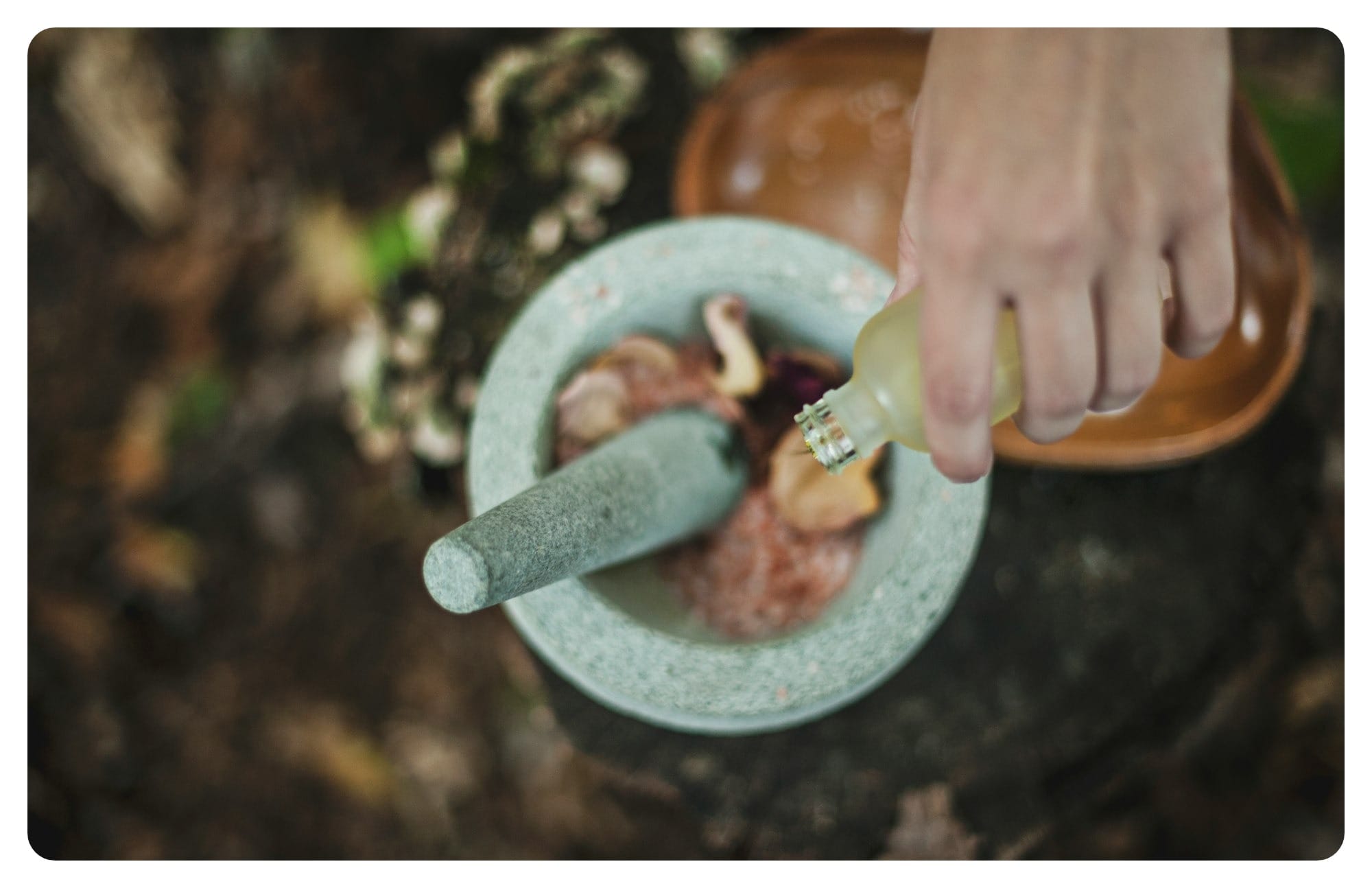 high angle photo of person pouring liquid from bottle inside mortar and pestle