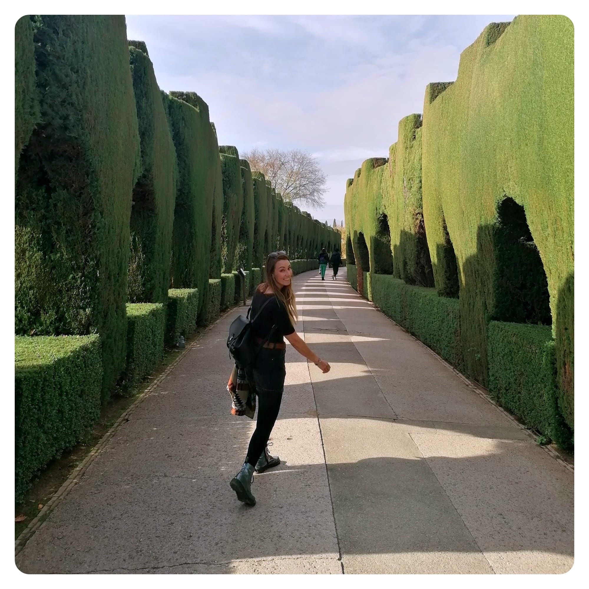 vanlavita woman walking in between hedges in the alhambra, granada