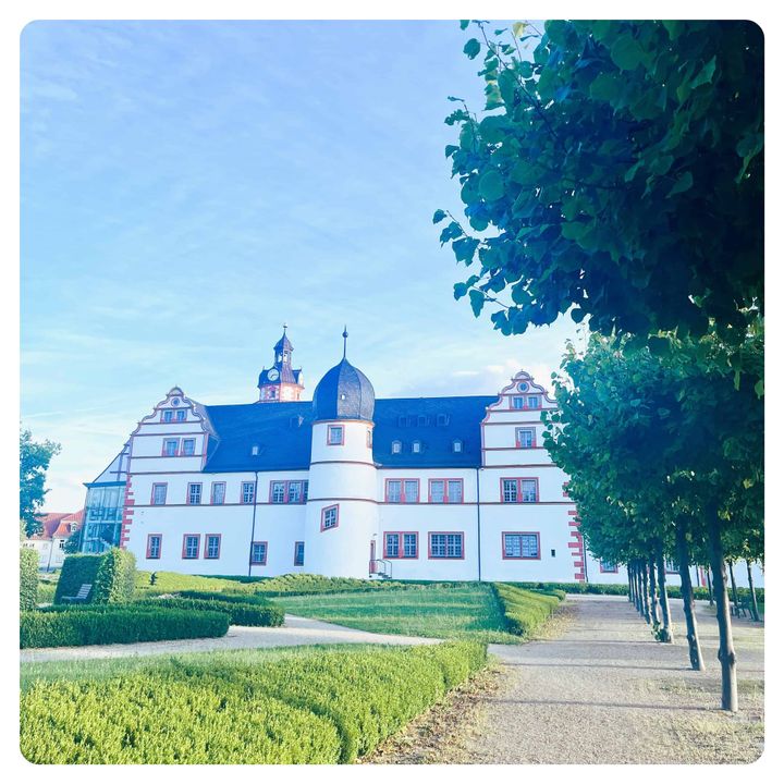 white castle with black roof in from of green grass lawn in Ohrdruf, Germany