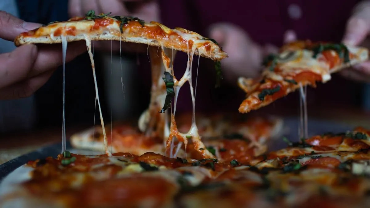 Una persona toma una rebanada de una pizza compartida
