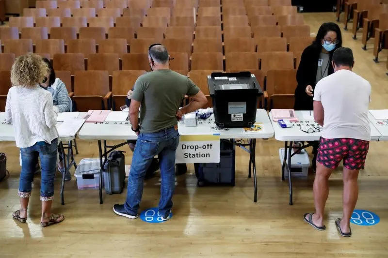 ELECCIONES. Las personas se registran con los trabajadores electorales antes de emitir sus votos en Sherman Oaks, California,