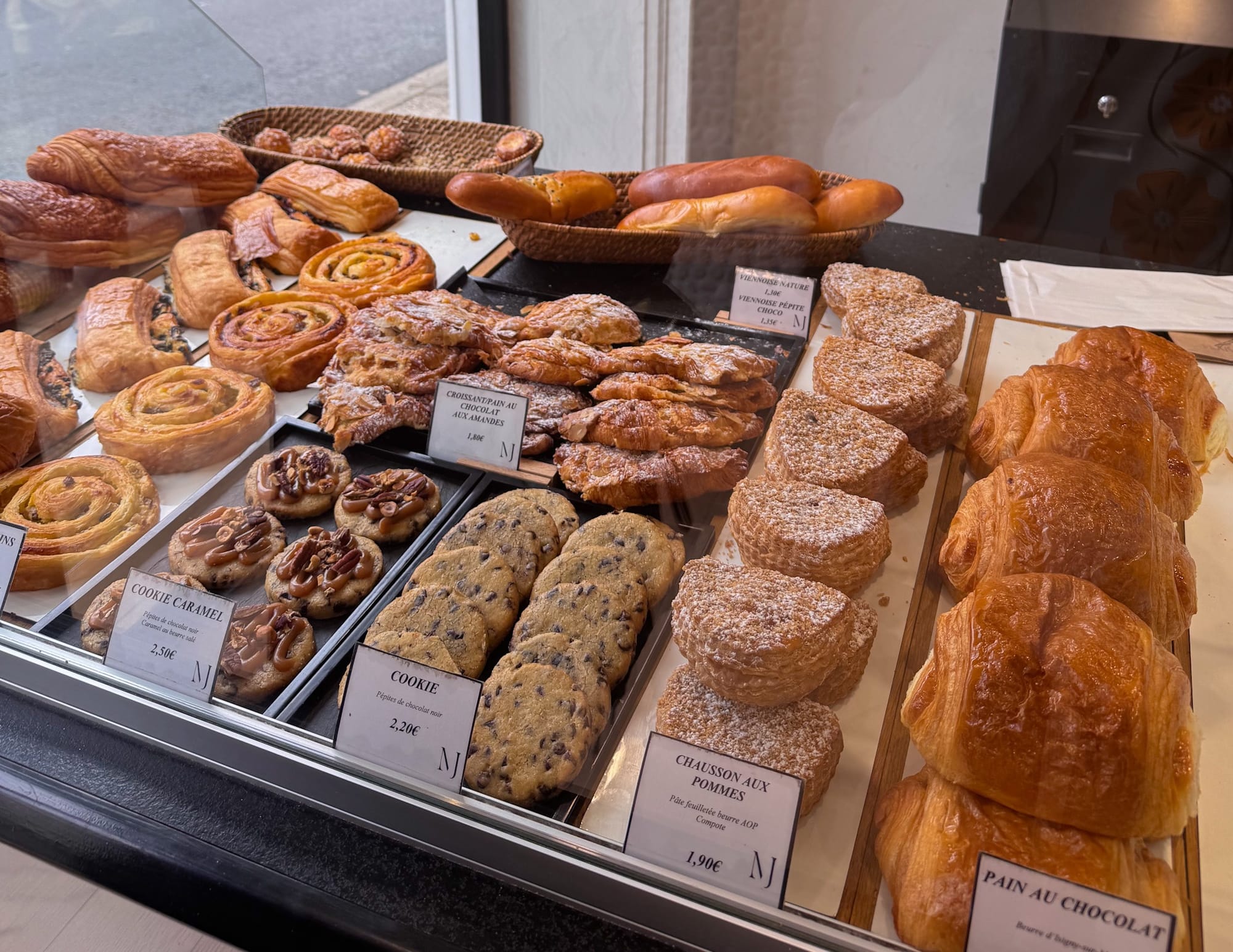 Fresh croissants, pain au chocolat, cookies, and traditional French pastries displayed inside Maison Piquenot bakery in Étretat, France.