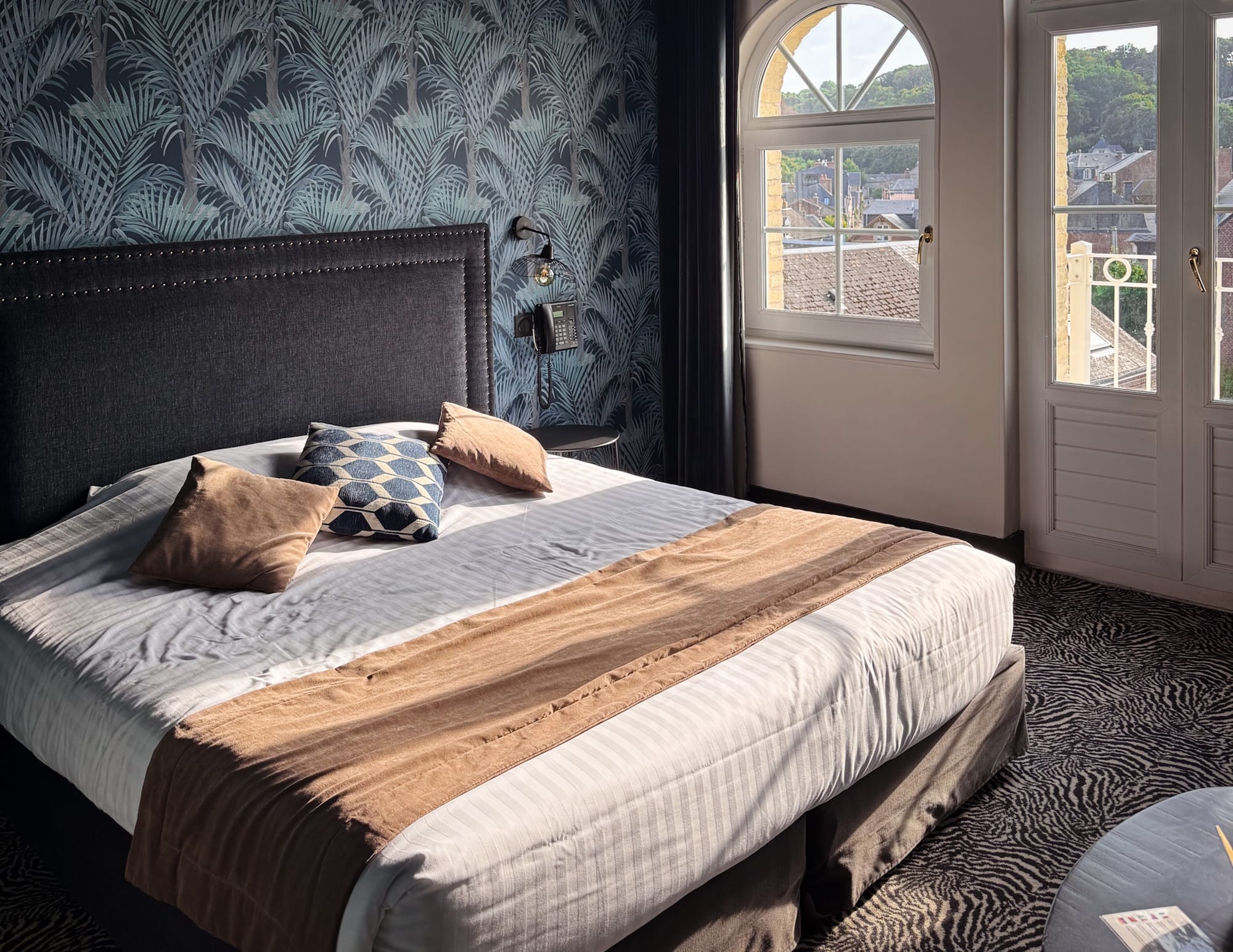 A stylish guest room at Hotel Villa 10 in Étretat, France, featuring modern décor and views over the town.