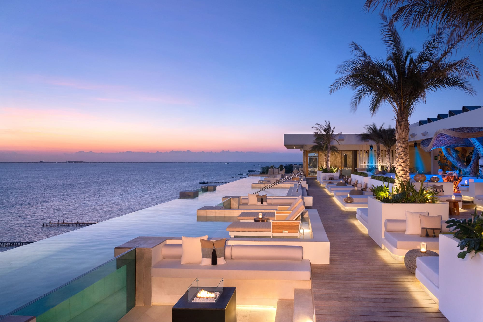 Infinity pool overlooking the Caribbean Sea at Impression Isla Mujeres by Secrets with modern lounge seating and sunset views.